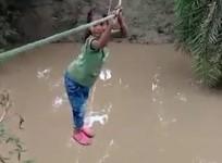 Children go to school by crossing the river with a rope.
