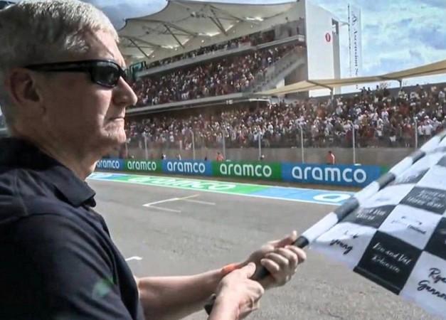 Apple CEO Tim Cook waves checkered flag at Formula 1 Grand Prix.