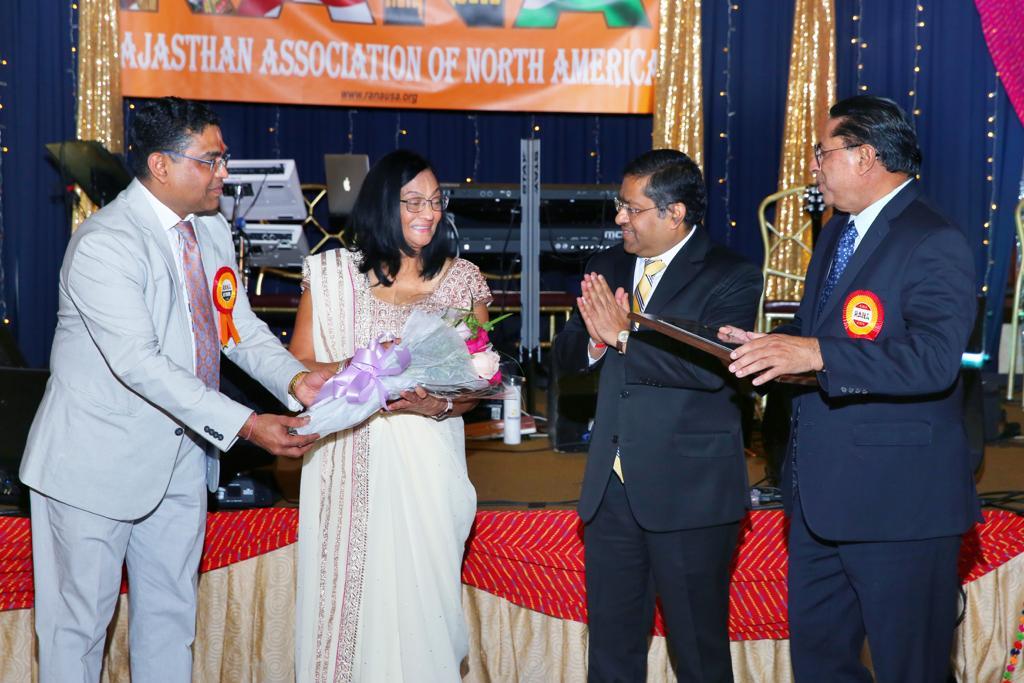 Counsel General of India, New York, Randhir Jaiswal, giving plaque to Dr Raj Bansal, Mrs Raj Bansal and RANA joint treasurer Dr Sharad Kothari giving flowers to Mrs Raj Bansal.