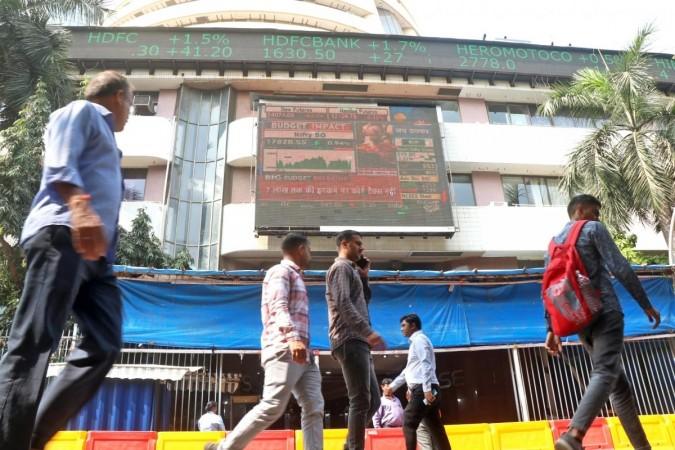 Mumbai: People walk past a screen showing stock market goes up outside BSE building at Dalal Street