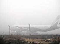 An airplane stands at the airport as fog engulfs the area on a cold winter morning