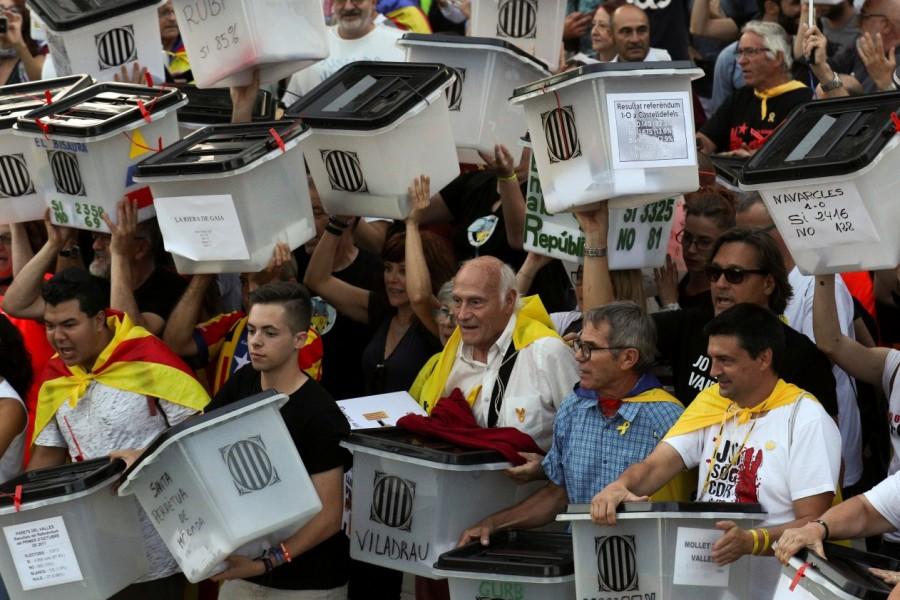 Protestors carry ballot boxes used during Catalonia's banned Catalan referendum anniversary,Riot police,Catalonia regional parliament,Barcelona,demonstration,Catalan anniversary