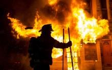 A Baltimore firefighter attacks a fire at a convenience store and residence during clashes after the funeral of Freddie Gray in Baltimore, Maryland in the early morning