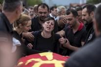 The wife (C) of killed policeman from special unit Tigers Zarko Kuzmanovski mourns next to his coffin draped with the Macedonian flag during his funeral in the village of Brvenica,