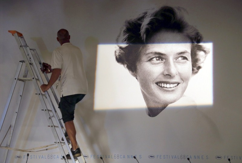 A worker sets up a giant canvas of the official poster of the 68th Cannes Film Festival, featuring late actress Ingrid Bergman, inside the press conference room at the Festival Palace in Cannes Gearing Up for Cannes Film Festival 2015,68th Cannes Film Festival 2015,Cannes Film Festival 2015,French Riviera town,Cannes Film Festival pics,Cannes Film Festival images,Cannes Film Festival,2015 Cannes Film Festival,Festival de Cannes 2015,cannes film