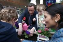 Britain's Prime Minister David Cameron plants flowers with children and Employment Minister Priti Patel (R) during a visit to a children's nursery in London