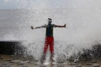 A boy gets drenched in a large wave during high tide at a sea front in Mumbai,