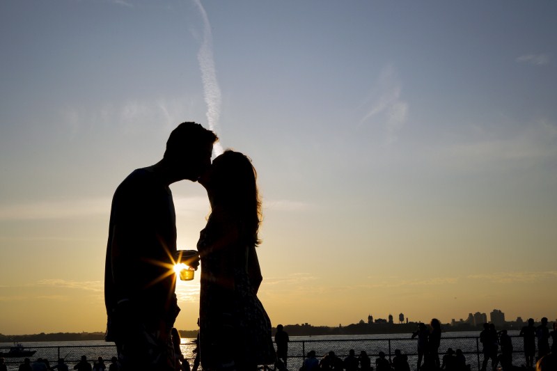 A couple kiss while they enjoy a sunny afternoon during the solstice day at Governors Island in New York Couple kiss,Couple kiss during the solstice day at Governors Island,solstice day at Governors Island,Governors Island,solstice day,Couple kisses during the Solstice day at Governors Island
