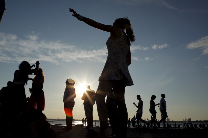 A woman dances as people enjoy a sunny afternoon during the solstice day at Governors Island in New York Couple kiss,Couple kiss during the solstice day at Governors Island,solstice day at Governors Island,Governors Island,solstice day,Couple kisses during the Solstice day at Governors Island