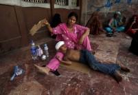 A woman uses a piece of cardboard to fan her son, while waiting for their turn for a medical checkup