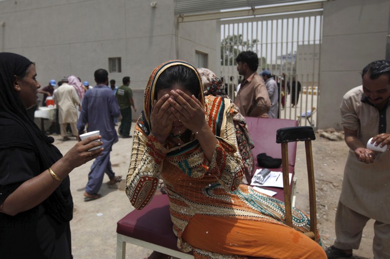 A woman wets her face to cool off, while sitting outside Jinnah Postgraduate Medical Centre Pakistan Heat Wave,Heat Wave,Pakistan Heat Wave Kills Hundreds,Pakistan,Karachi,Karachi Heat Wave