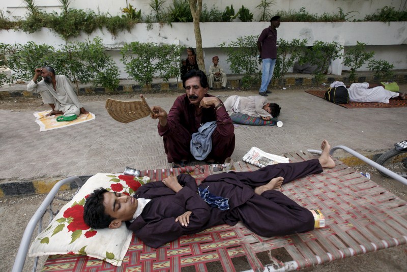 A man uses a hand-held fan to cool down his son, while waiting for their turn for a medical checkup Pakistan Heat Wave,Heat Wave,Pakistan Heat Wave Kills Hundreds,Pakistan,Karachi,Karachi Heat Wave