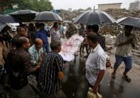 People carry the body of a victim who died after consuming bootleg liquor