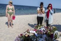 Women pray near bouquets of flowers laid on the beach of the Imperial Marhaba resort
