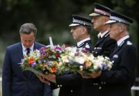 Britain's Prime Minister David Cameron bows as he stands with police officers after laying a wreath at the memorial to victims