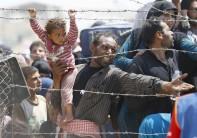 A Syrian refugee holds onto his daughter as he waits to cross into Turkey at Akcakale border gate