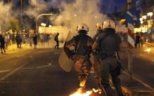 Masked anti-establishment youths and anti-austerity protesters face riot police during clashes in Athens