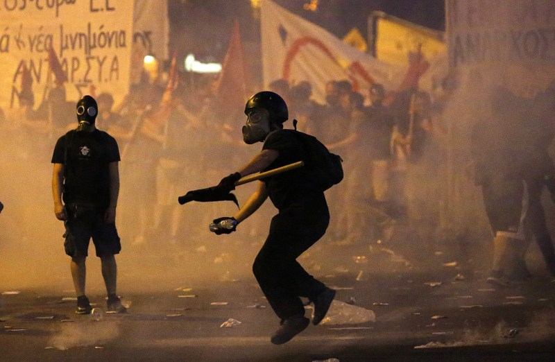 A masked youth hurls a projectile at riot police during clashes in Athens Protests Turn Violent in Greece,Protests in Greece,Anti-austerity movement in Greece,Greece protests turn violent,bailout deal,amid protests,anti-establishment protesters