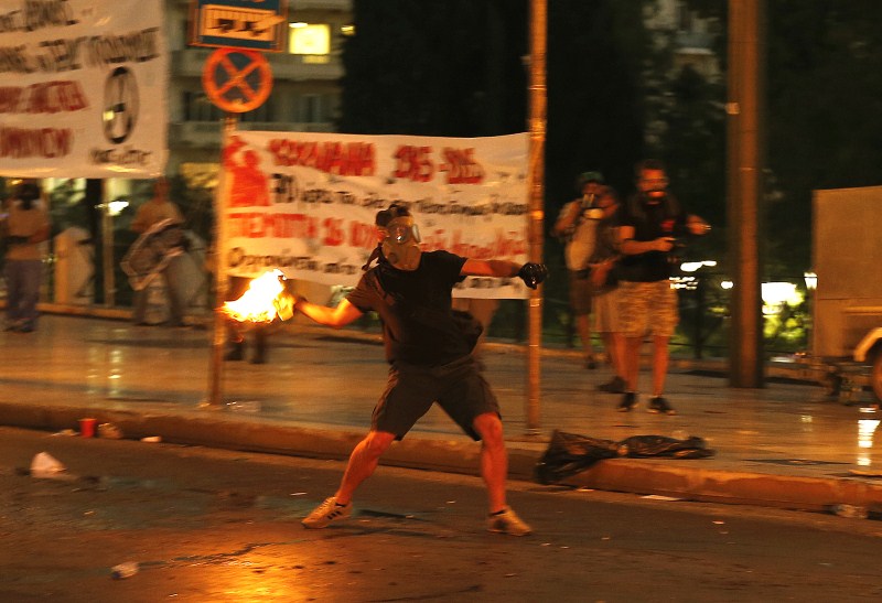 A masked youth hurls a petrol bomb to riot police during clashes in Athens Protests Turn Violent in Greece,Protests in Greece,Anti-austerity movement in Greece,Greece protests turn violent,bailout deal,amid protests,anti-establishment protesters