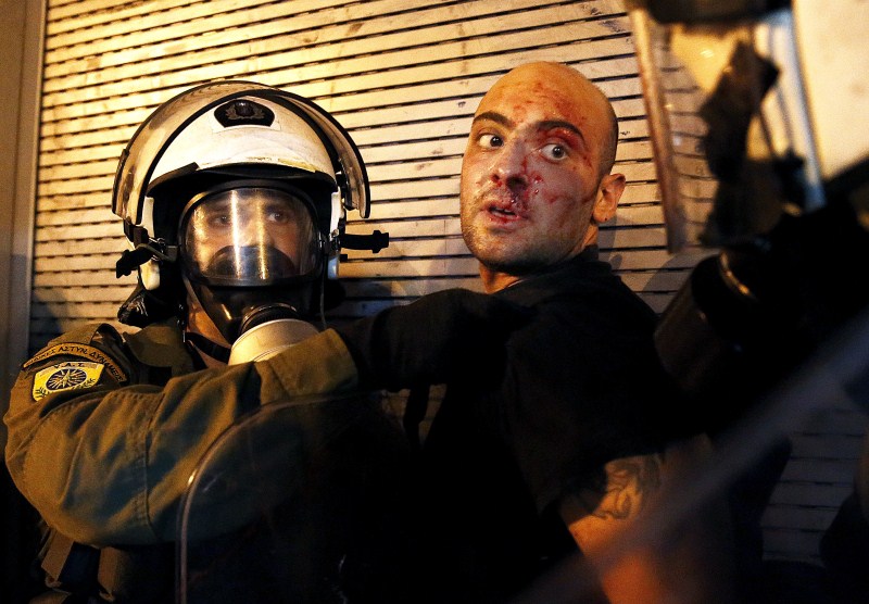 A protester bleeds as he is arrested by riot police following clashes in Athens Protests Turn Violent in Greece,Protests in Greece,Anti-austerity movement in Greece,Greece protests turn violent,bailout deal,amid protests,anti-establishment protesters
