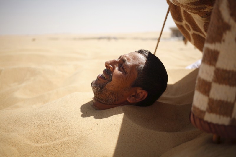Patients relax in the shade before treatment, which includes massages by the feet of health workers who also submerge their patients up to their neck in the desert. Patients drink mint tea in tents following the treatment. Hot Sand Baths of Siwa,Hot Sand Baths,Patients Sand Baths of Siwa,desert,Patients,treatment,sand bath treatment,sand bath