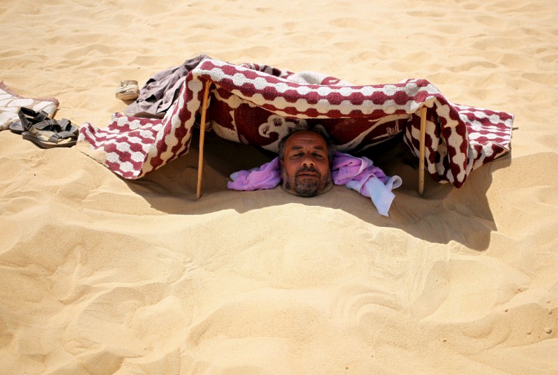 Patients relax in the shade before treatment, which includes massages by the feet of health workers who also submerge their patients up to their neck in the desert. Patients drink mint tea in tents following the treatment. Hot Sand Baths of Siwa,Hot Sand Baths,Patients Sand Baths of Siwa,desert,Patients,treatment,sand bath treatment,sand bath
