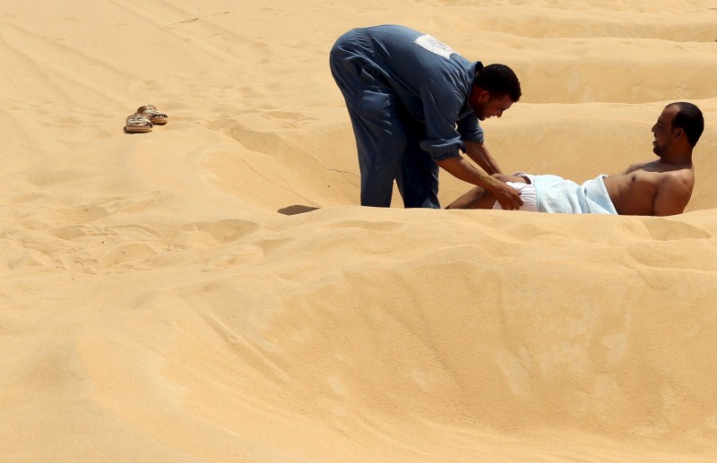 Patients relax in the shade before treatment, which includes massages by the feet of health workers who also submerge their patients up to their neck in the desert. Patients drink mint tea in tents following the treatment. Hot Sand Baths of Siwa,Hot Sand Baths,Patients Sand Baths of Siwa,desert,Patients,treatment,sand bath treatment,sand bath