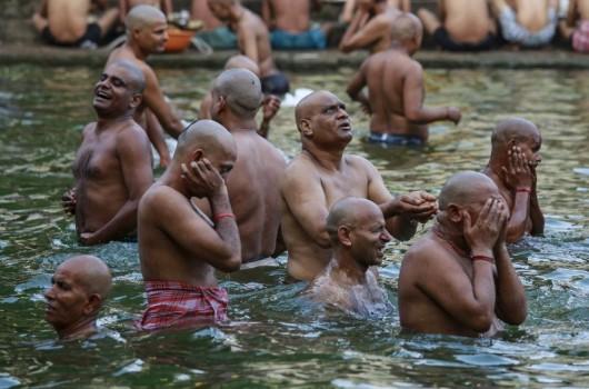 Hindu devotees pray in a holy pond on the auspicious day of Mahalaya in Mumbai, India, on 12 October 2015. Hindus offer prayers with holy water after taking a dip in the river to honor the souls of their departed ancestors during Mahalaya, which is also called Shraadh or Pitru Paksha.