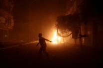 A man runs near a burning car after an airstrike in the rebel held Douma neighborhood of Damascus.