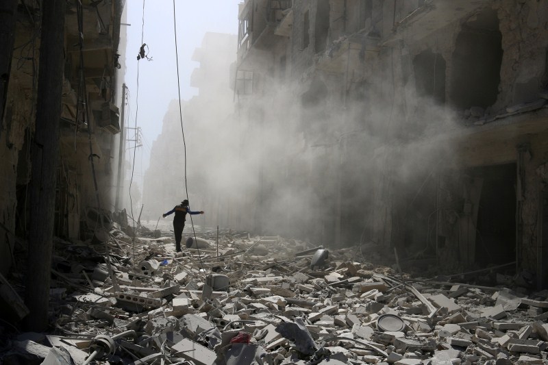 A man walks on the rubble of damaged buildings after an airstrike on the rebel held al-Qaterji neighbourhood of Aleppo. Air strikes,rebel-held Syria,Syria conflict,Syrian government forces,Syrian army,Air strikes pound rebel-held Aleppo