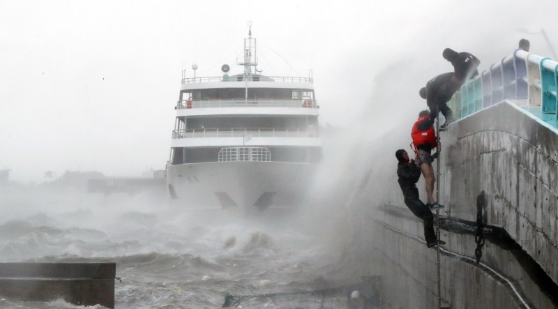 A crew member (wearing a red jacket) of a passenger ship stranded by typhoon Chaba is rescued by maritime police officers in Yeosu, South Korea, October 5, 2016. Typhoon Chaba,Typhoon Chaba batters South Korea,Typhoon Chaba hits South Korea,heavy rain in South Korea,flooding in South Korea,Typhoon Chaba batters South Korea and heads to Japan,Typhoon Chaba photos,Typhoon Chaba pics,Typhoon Chaba images,Typhoon Chab