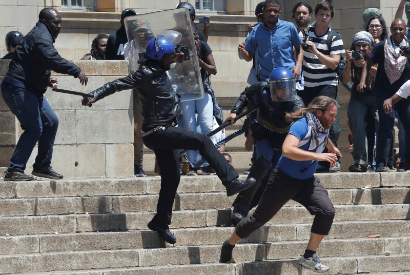 A riot police officer and private security guards attempt to detain a student as they clashed during protests with students demanding free education on Monday at the Johannesburg's University of the Witwatersrand, South Africa. Student protests,Student protests in South Africa,university education,Students demanding free education,Johannesburg University