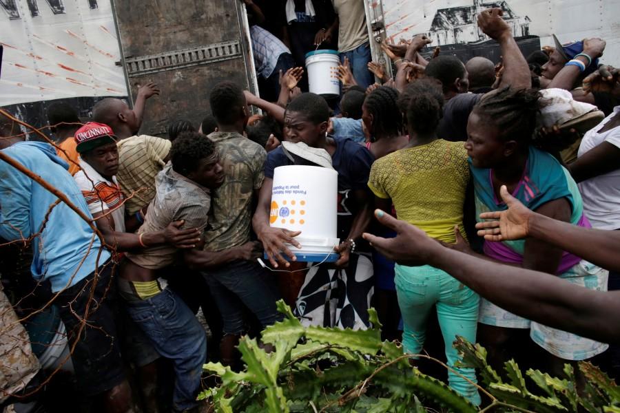 People fight for a bucket of supplies during a distribution after Hurricane Matthew in Torbeck, Haiti. Haiti,Hurricane Matthew,Hurricane,acter Hurricane Matthew