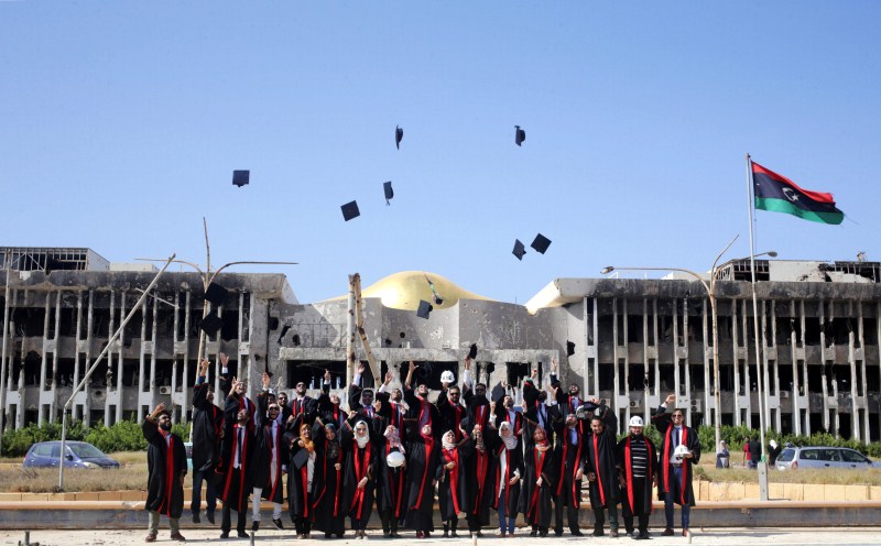 New graduates of Engineering and Law faculties at Benghazi University celebrate as they pose in front of damaged buildings at their university's former headquarters, which was destroyed during clashes in 2014, between members of the Libyan National Army and Shura Council of Libyan Revolutionaries, an alliance of former anti-Gaddafi rebels who have joined forces with Islamist group Ansar al-Sharia, in Benghazi, Libya. College graduates,Benghazi University,Libyan school,Student clashes,College graduates in a war zone
