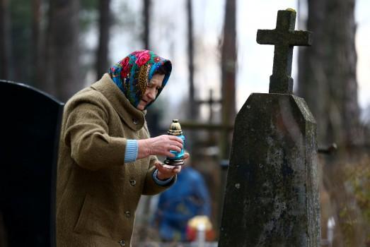 A woman lights a candle on a grave at a cemetery in the village of Ivenets, Belarus.