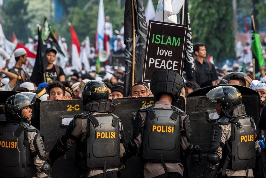Anti-riot policemen stand guard as Muslim hardline protesters attend a protest against Jakarta's incumbent governor Basuki (Ahok) Tjahaja Purnama, an ethnic Chinese Christian running in the upcoming election, in Jakarta, Indonesia. Hardline Muslims,massive rally in Indonesia,Muslim protesters,hardline Muslim protesters rally,hardline Muslim protesters,Koran,Islam Love Peace