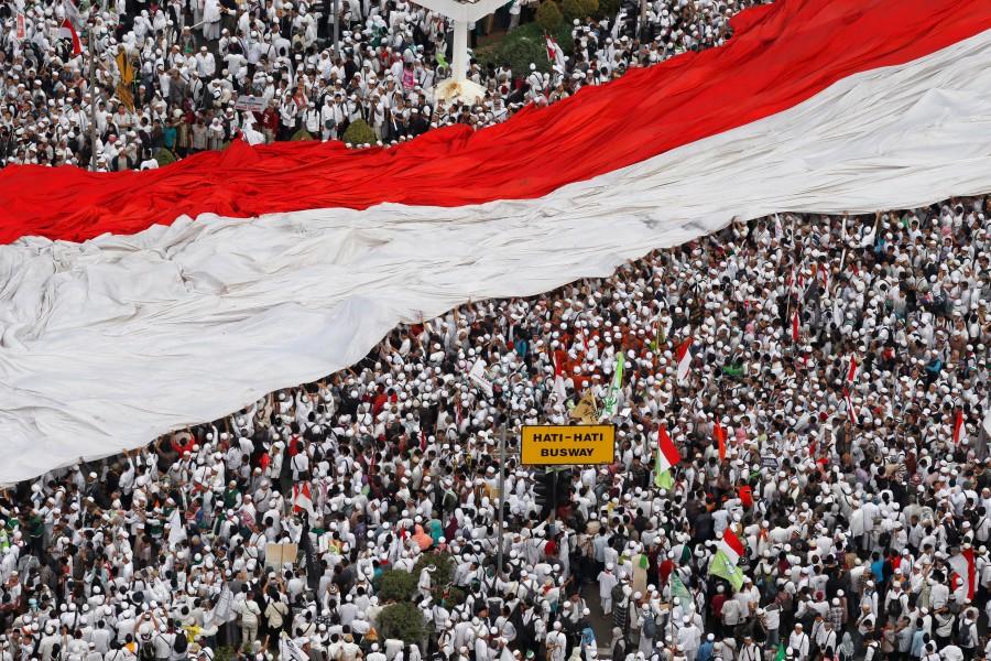 Members of hardline Muslim groups hold a big national flag as they attend a protest against Jakarta's incumbent governor Basuki Tjahaja Purnama, an ethnic Chinese Christian running in the upcoming election, in Jakarta, Indonesia. Hardline Muslims,massive rally in Indonesia,Muslim protesters,hardline Muslim protesters rally,hardline Muslim protesters,Koran,Islam Love Peace