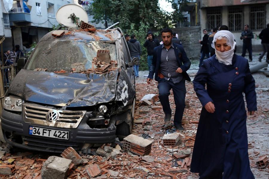 People walk past a damaged car after a blast in the Kurdish-dominated southeastern city of Diyarbakir, Turkey. Car bomb,Car bomb explodes after Turkey detains,Car bomb explodes in Turkey,pro-Kurdish lawmakers,Turkey,blast in Diyarbakir,Diyarbakir blast
