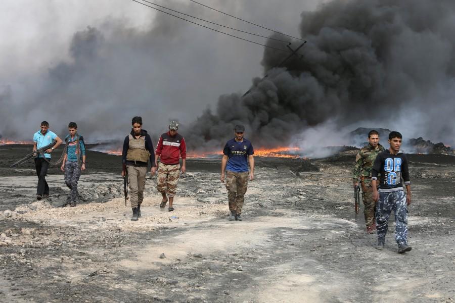 Tribal fighters walk as fire and smoke rises from oil wells, set ablaze by Islamic State militants before IS militants fled the oil-producing region of Qayyara. Iraqi security forces,Iraqi security,Islamic State militants,Islamic militants,Iraqi security forces launch,Mosul,On the frontlines of Mosul