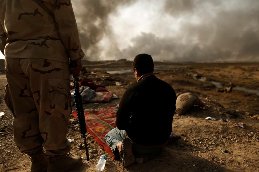 An Iraqi soldier stands next to a detained man accused of being an Islamic State fighter at a check point in Qayyara, south of Mosul. Iraqi security forces,Iraqi security,Islamic State militants,Islamic militants,Iraqi security forces launch,Mosul,On the frontlines of Mosul