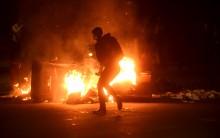 A woman passes burning garbage during a demonstration in Oakland, California, following the election of Donald Trump as president of the United States.
