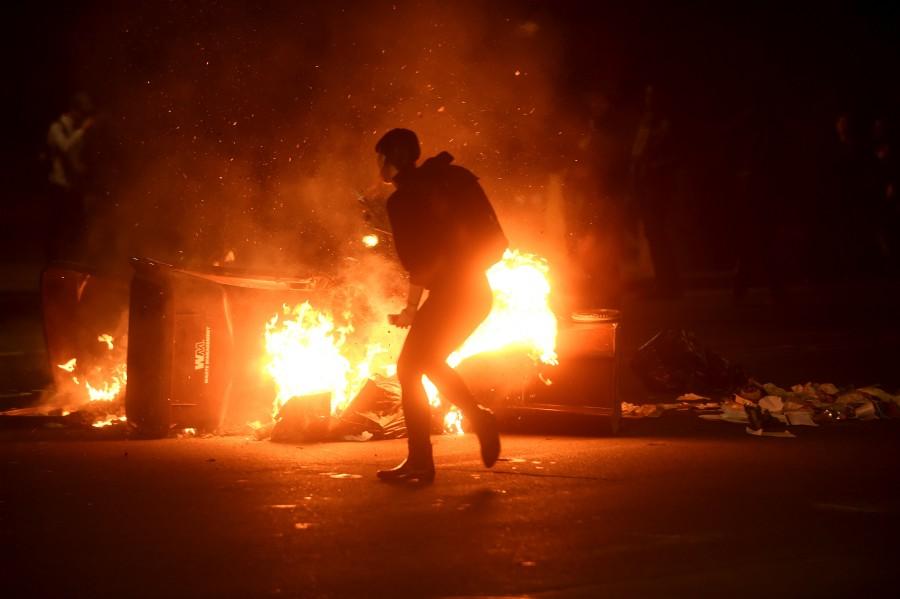 A woman passes burning garbage during a demonstration in Oakland, California, following the election of Donald Trump as president of the United States. Donald Trump,Donald Trump as 45th US President,45th US President,US President,America divided after the Election,People react after the results,America divided after election