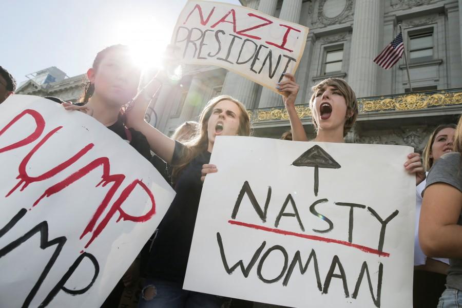 Hope Robertson, 17, center, and Cat Larson, 17, right, of Mission High School, hold up signs in front of City Hall in protest of the election in San Francisco, California. Anti-Trump protests,Trump protests,Donald Trump,Donald Trump protest,presidential election victory