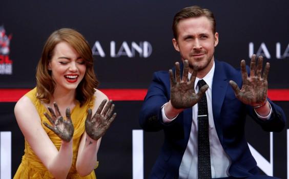 Photos of Emma Stone and Ryan Gosling place their hands in cement at the TCL Chinese theatre in Hollywood.