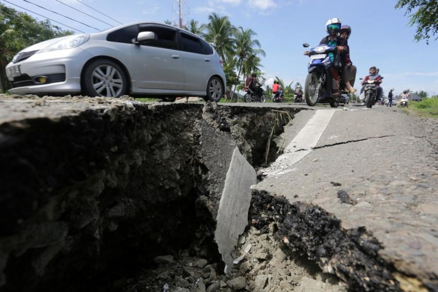 Motorcyclists pass a damaged section of a road following an earthquake in Meuredu, Pidie Jaya, in the northern province of Aceh, Indonesia. Quake Strikes Indonesia,Strong Quake,Strong Quake Strikes Indonesia,strong earthquake,Sumatra,Indonesia,Indonesia earthquake,Indonesia earthquake pics,Indonesia earthquake images,Indonesia earthquake photos,Indonesia earthquake stills