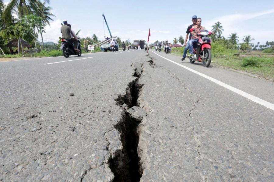 Motorcyclists pass a damaged section of a road following an earthquake in Meuredu, Pidie Jaya, in the northern province of Aceh, Indonesia. Quake Strikes Indonesia,Strong Quake,Strong Quake Strikes Indonesia,strong earthquake,Sumatra,Indonesia,Indonesia earthquake,Indonesia earthquake pics,Indonesia earthquake images,Indonesia earthquake photos,Indonesia earthquake stills