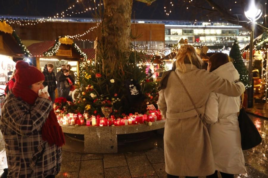 People mourn beside flowers and candles placed at the Christmas market at Breitscheid square. Berlin opens Christmas market,Berlin market,Christmas market,Christmas,Christmas 2016,Berlin Attack,Berlin Christmas market attack,berlin truck attack,Berlin Christmas market