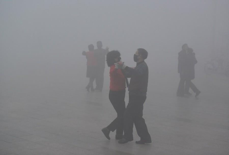 People wearing masks dance at a square among heavy smog during a polluted day in Fuyang, Anhui province. China is in the third year of a war on pollution aimed at reversing the damage done to its skies, soil and water after decades of untrammeled economic growth. China,China smoggy skies,smoggy skies,soil and water,economic growth