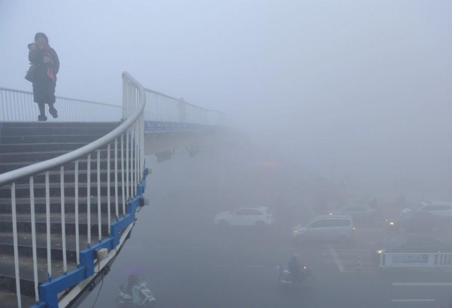 A woman walks past a bridge among heavy smog during a polluted day in Fuyang, Anhui province. China,China smoggy skies,smoggy skies,soil and water,economic growth