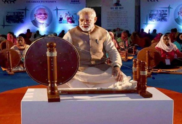 Most employees and officials were taken aback to see the cover photo of the calendar and diary showing Modi weaving khadi on a large 'charkha', in the same iconic pose as Gandhiji. While Gandhi's historic picture weaving khadi on a simple wooden charkha, wearing his trademark loin cloth, is legendary and imprinted in the minds of the masses since generations, Modi comes across in his signature attire of kurta-pyjama-waistcoat, weaving khadi on a slightly modernised charkha. Narendra Modi,Modi,Narendra Modi replaces Gandhi,Modi replaces Gandhi,Khadi Udyog,Khadi Udyog calendar,Mahatma Gandhi,Father of the Nation,Khadi Village Industries Commission,PM Narendra Modi